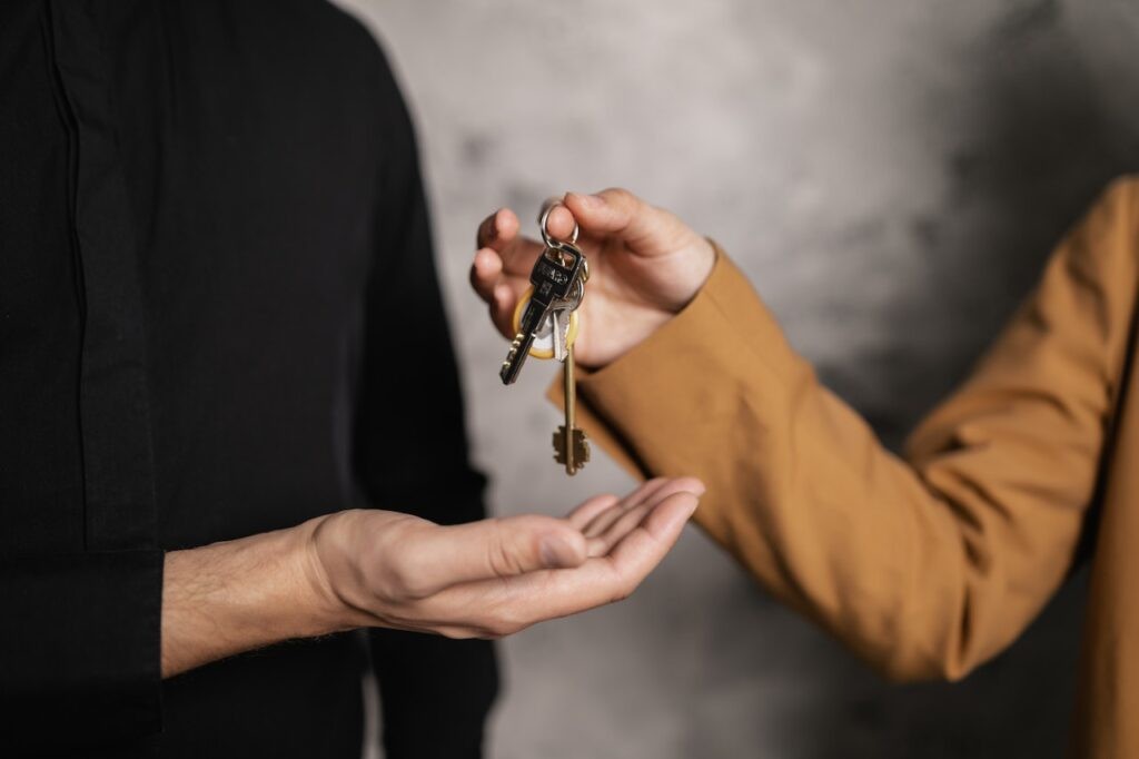 A person giving house keys to another person, symbolic of a new home.