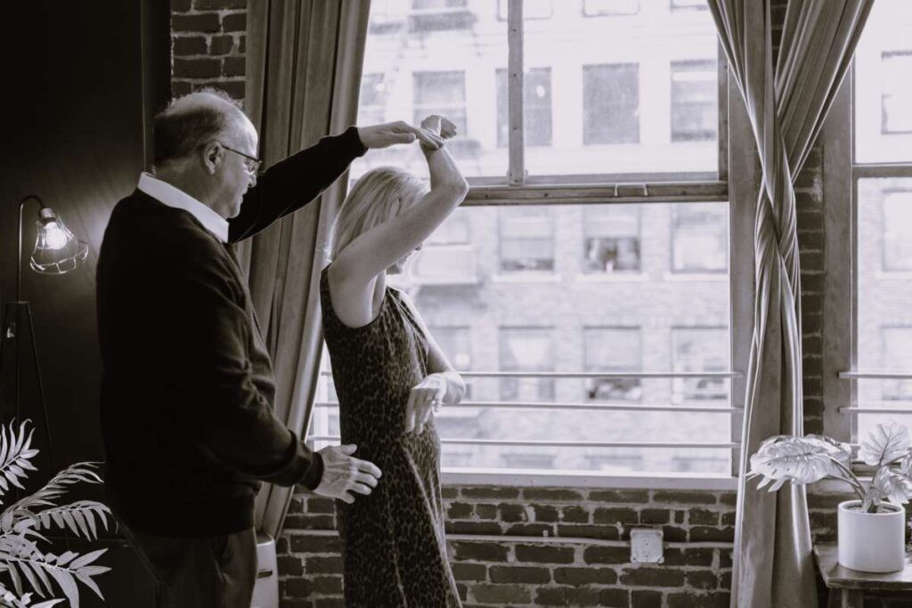 A couple dancing in front of a window.